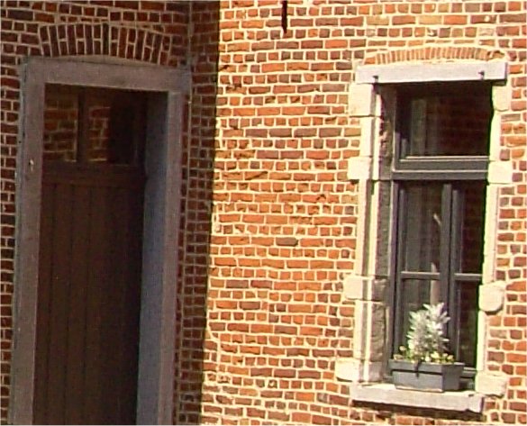 rechts raamopening oud gedeelte (pre-16de eeuw), links deuropening in arduin (18de eeuw)